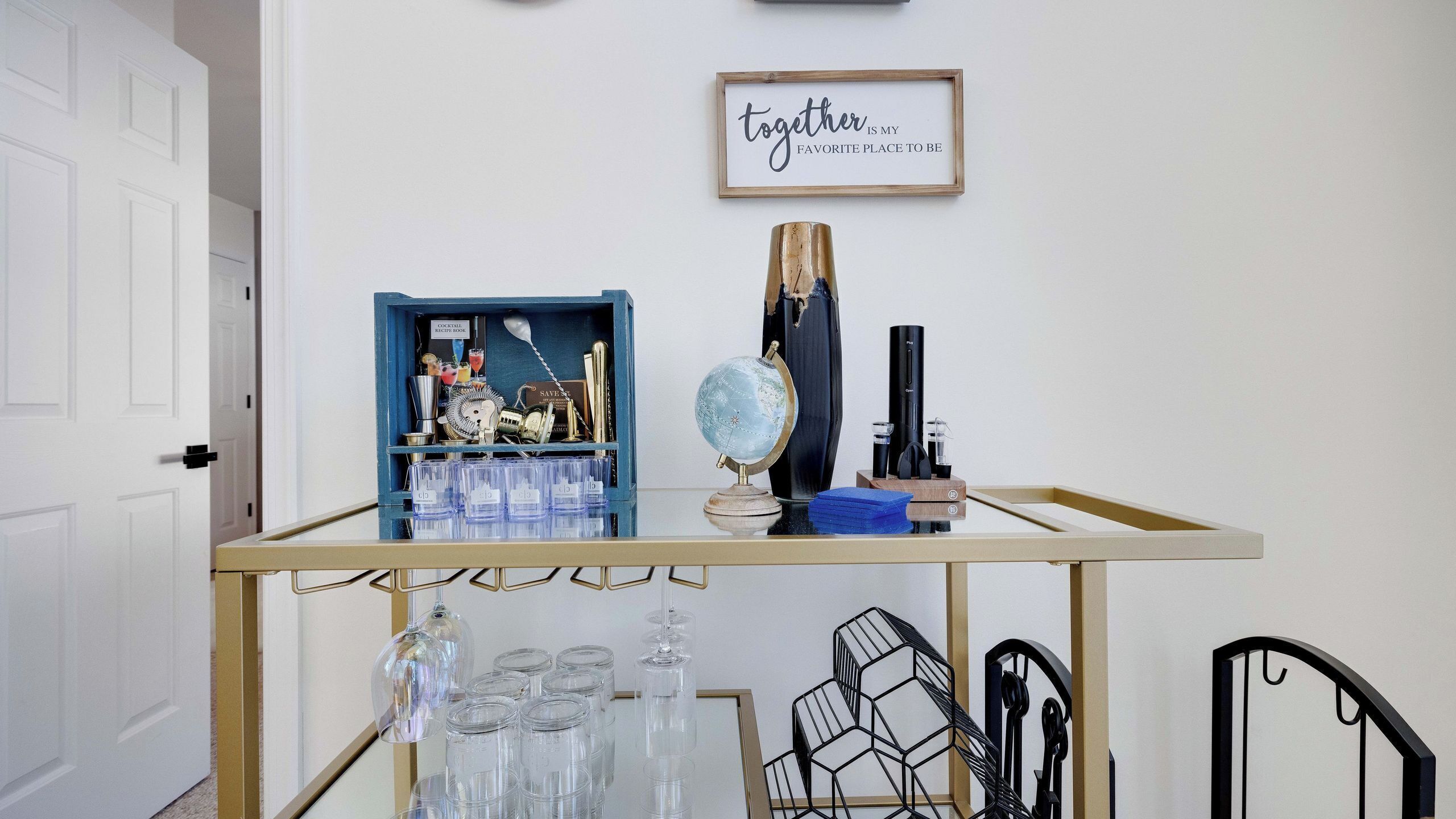 A bar cart with a cocktail recipe book, a globe, and a vintage radio.