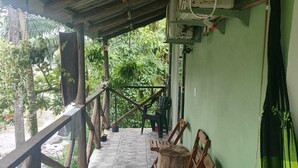 A covered outdoor area with stone flooring, wooden furniture, and a potted plant. - Pousada beira rio  (Rodeio)