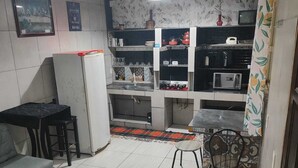 A compact living space with a kitchenette, a dining area, and a sofa. - Pousada beira rio  (Rodeio)