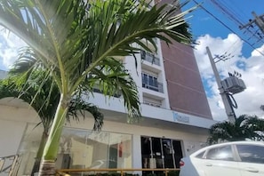 Un edificio de varios pisos con entrada visible y un coche estacionado.