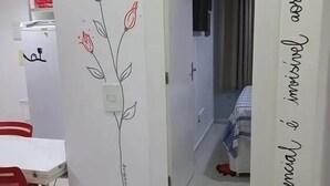 A room with a white wall featuring a simple line drawing of a rose and a mirror with a quote. - Flat -smart residence  (Teresina)
