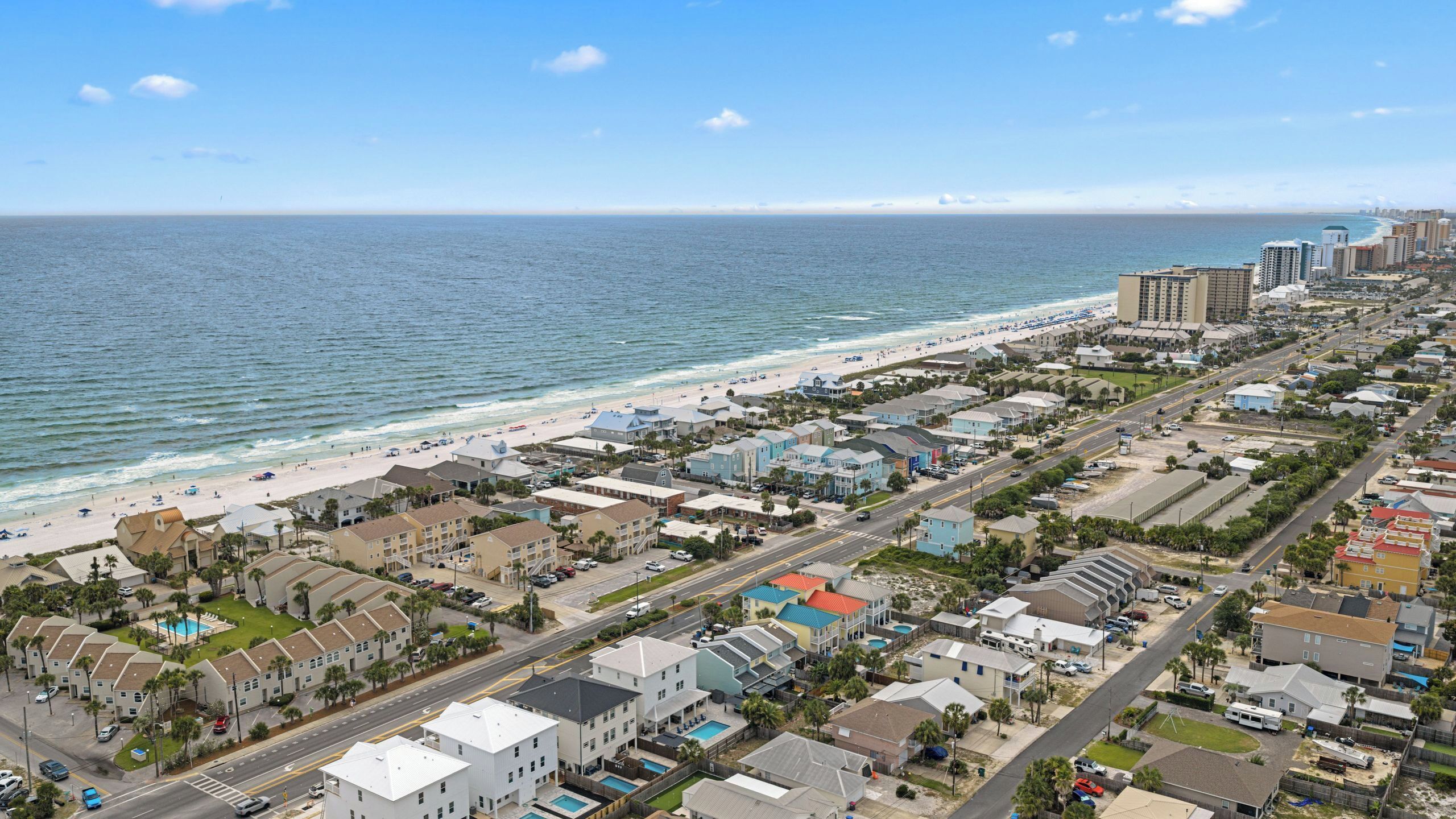 Eine Küstenstadt mit Strand, Wohnhäusern und einer Straße.