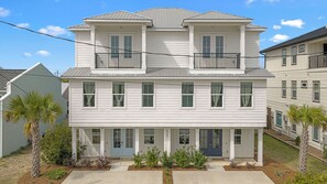 A two-story residential building with a front porch, a balcony on the upper floor, and a clear sky. - High Tide by Avantstay Luxe Beach Retreat Shared Pool + Hot Tub Walk to Beach (Panama City Beach)