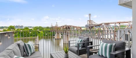 Un balcón con mobiliario exterior, vista a un río y un puente al fondo.