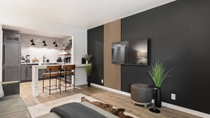 A modern living room with a kitchen, a flat-screen TV, and a sofa. - Walk to Music Row and Vanderbilt, Only 1 Mile to Broadway (Nashville)