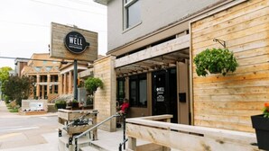 A building with a sign reading 'The Well Coffeehouse,' a staircase leading to a wooden deck, and a person sitting on a bench. - Walk to Music Row and Vanderbilt, Only 1 Mile to Broadway (Nashville)