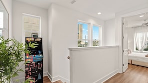 A modern bedroom with a window, a bed, and a gaming console. - Low Tide by Avantstay Walk to Beach Shared Pool + Hot Tub Near St. Andrews (Panama City Beach)