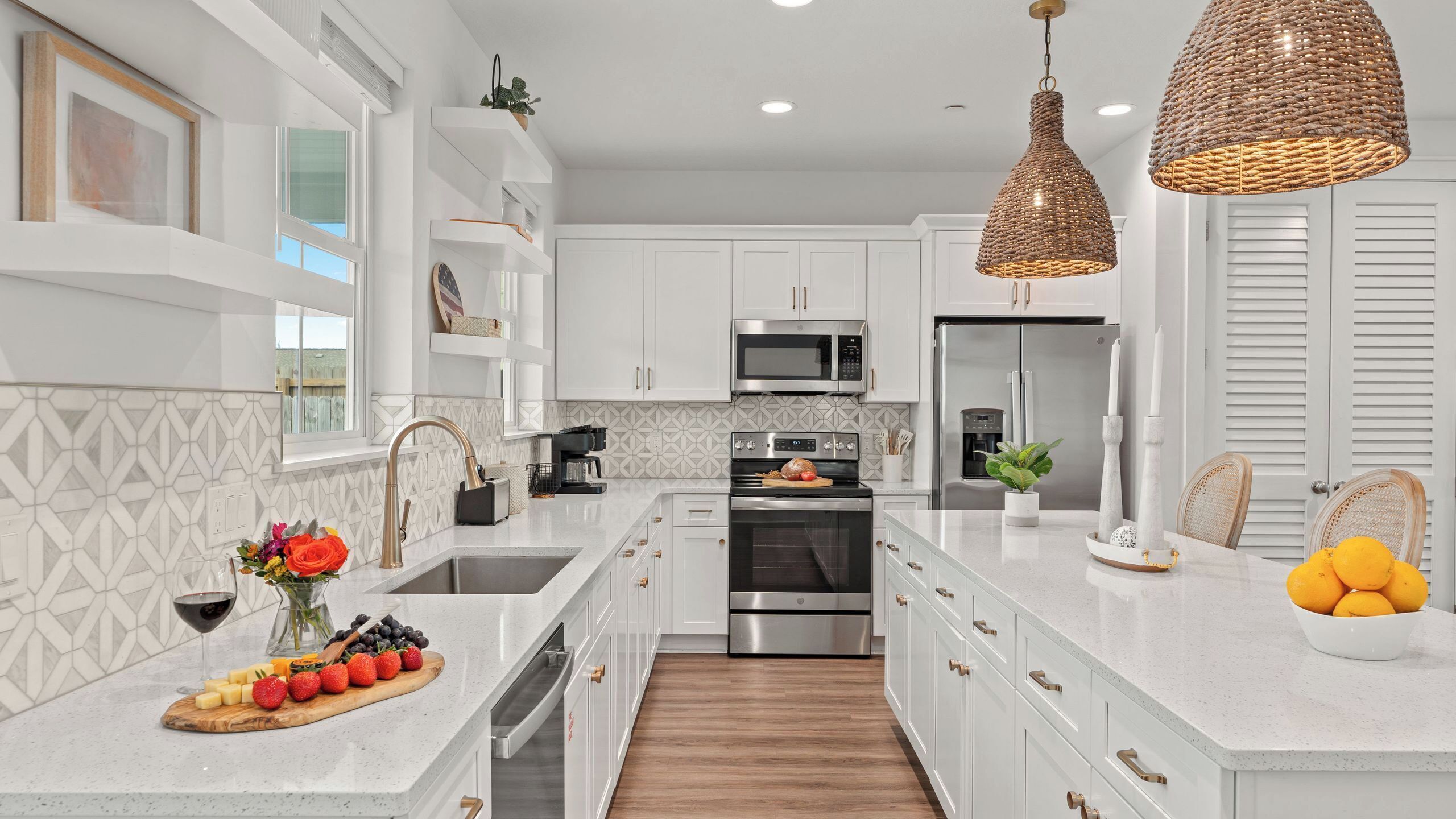 Una cocina moderna con armarios blancos, electrodomésticos de acero inoxidable y una isla central con una exhibición de frutas.