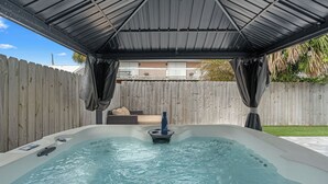 A hot tub under a covered area with a wooden fence in the background. - Low Tide by Avantstay Walk to Beach Shared Pool + Hot Tub Near St. Andrews (Panama City Beach)