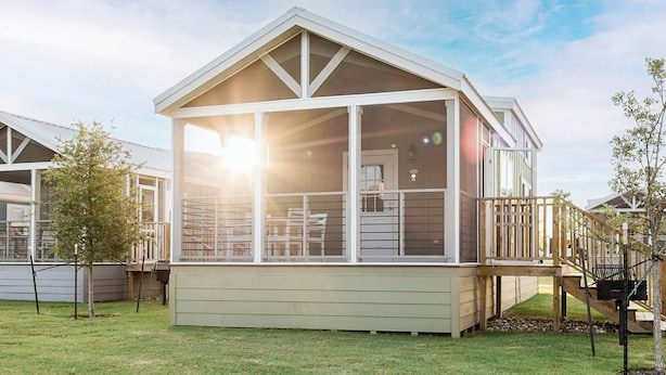 A single-story house with a large glass front, a deck, and a wooden staircase. - Pet-Friendly Cabin w/ Loft | Pool, Fire Pit & River (Hutto)