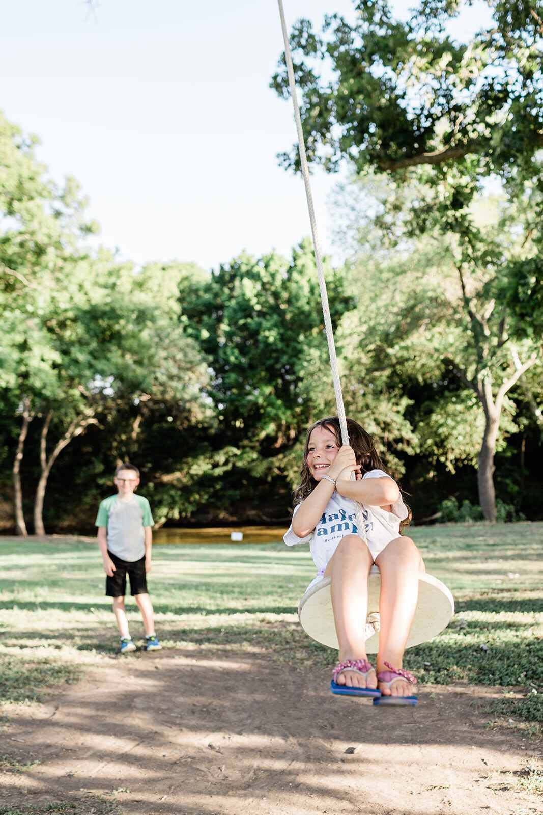A swing set in a park with a grassy area and trees in the background.