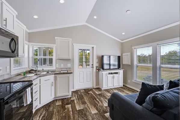 A modern kitchen with white cabinets, a built-in microwave, and a large window.