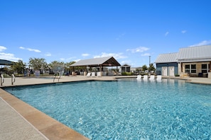 A swimming pool with a covered seating area and a building with a metal roof.
