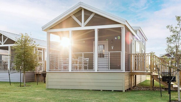 A single-story house with a large glass front, a deck, and a wooden staircase.