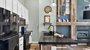 A modern kitchen with a central island, stainless steel appliances, and a wooden accent wall. - Serenity by the Slopes Steps to Trails + Free Bus to Slopes Balcony + Views (Vail)