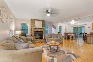 A living room with a fireplace, a dining area, and a kitchen.