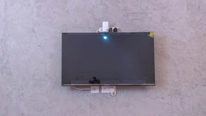 A flat-screen TV mounted on a wall with a power outlet below it. - The Woodlands Retreat (Chinhoyi)
