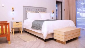 A bedroom with a bed, bedside tables, a wooden bench, and a window with curtains. - The Woodlands Retreat (Chinhoyi)