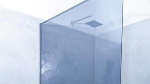 A glass-enclosed shower area with a visible showerhead and a control panel. - The Woodlands Retreat (Chinhoyi)