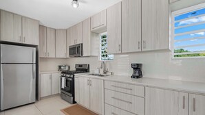 Une cuisine moderne dotée d’appareils électroménagers en acier inoxydable, de meubles de couleur bois clair et d’une grande fenêtre offrant une belle vue.