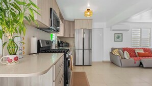Ett modernt kök med en central köksö, rostfria vitvaror och en matplats med en soffa.