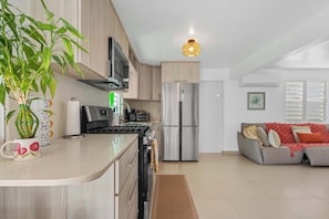 Eine moderne Küche mit Kochinsel, Edelstahlgeräten und einem Essbereich mit einer Couch.