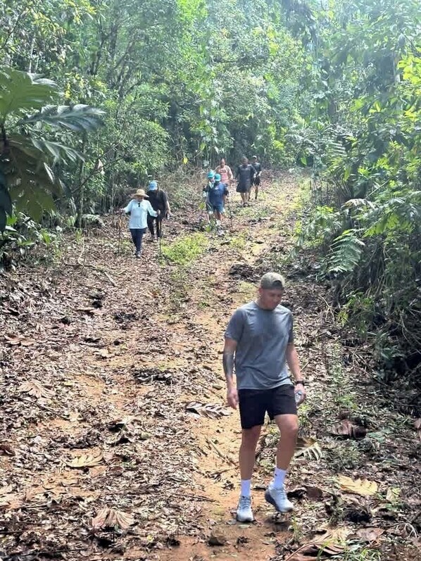 A forested hiking trail with people walking.