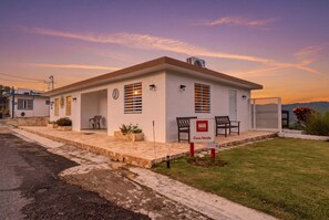 A single-story building with a flat roof, a covered porch with two chairs, and a sign reading 'Casa Verde'. - Casa Verde at Hacienda Serena w/ Mt. View + River (Las Marías)