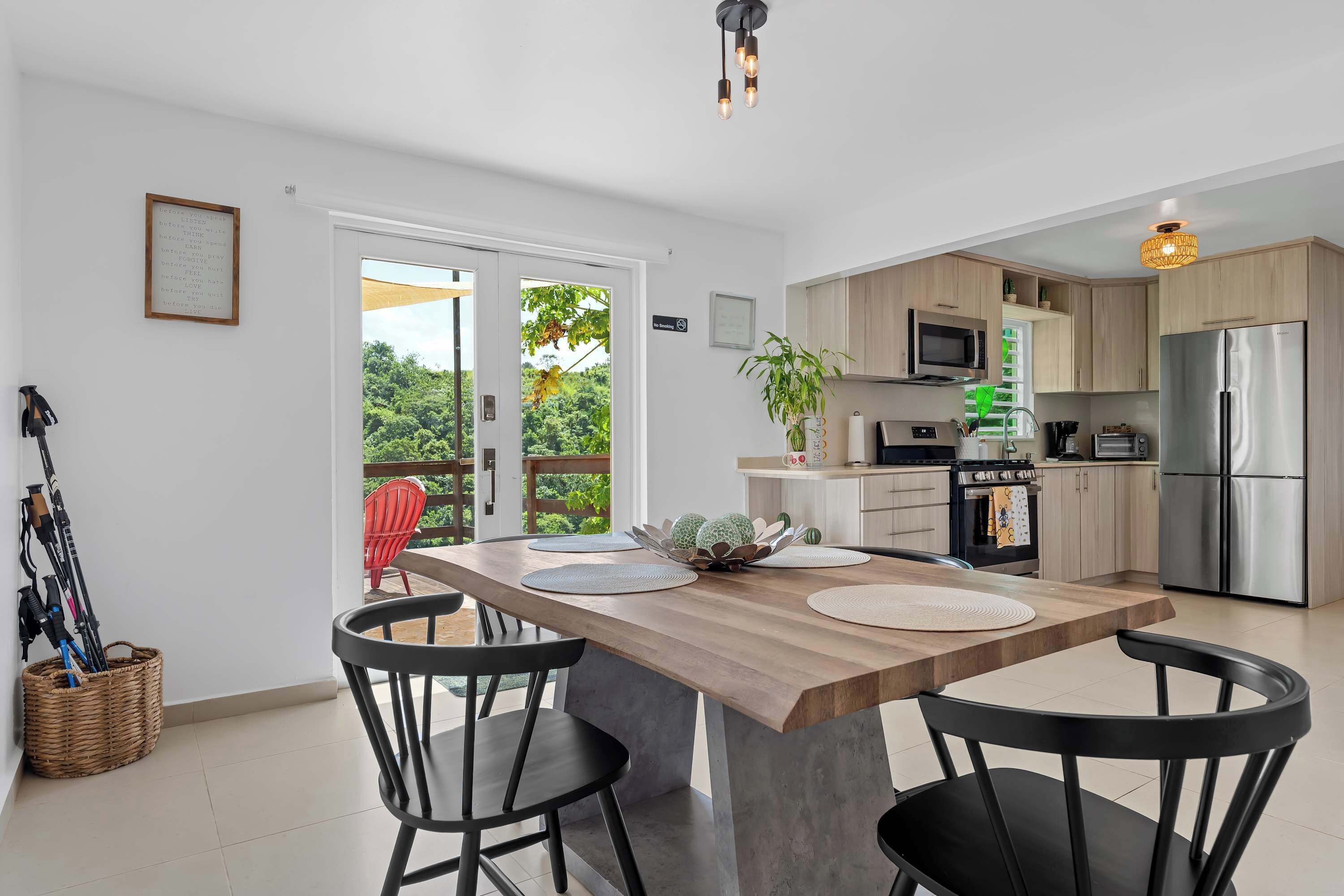 A modern kitchen with a central island, a dining area with chairs, and a view through a glass door.