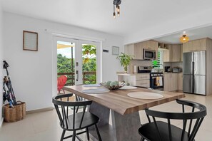 Una cocina moderna con una isla central, un comedor con sillas y vistas a través de un ventanal.