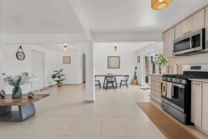 A modern kitchen with a stove, microwave, and cabinets. There is a dining area with a table and chairs. - Casa Verde at Hacienda Serena w/ Mt. View + River (Las Marías)