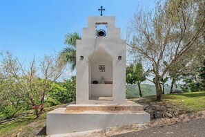 Une petite chapelle blanche, surmontée d’une croix, avec une cloche et une pancarte sur laquelle on peut lire : « LA GRÂCE EST PRÉSENTE ».