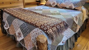 A bed with a quilt, wooden headboard, and a nightstand with a lamp. - Mazama Trails Laundry House-Dog Friendly&Close to Ski Trail! (Winthrop)