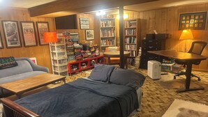 Una habitación acogedora con una cama, un escritorio, una silla, una estantería y un sofá.