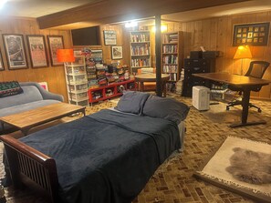 Ein gemütliches Zimmer mit Bett, Schreibtisch, Sessel, Bücherregal und einer Couch.