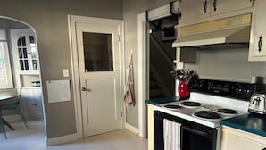 Una cocina con estufa, horno y un florero rojo en la encimera.