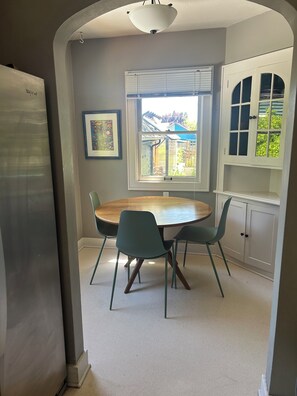 A dining area with a round table, two chairs, a window, and a cabinet. - Cozy home in Vibrant Whiteaker Neighborhood (Eugene)
