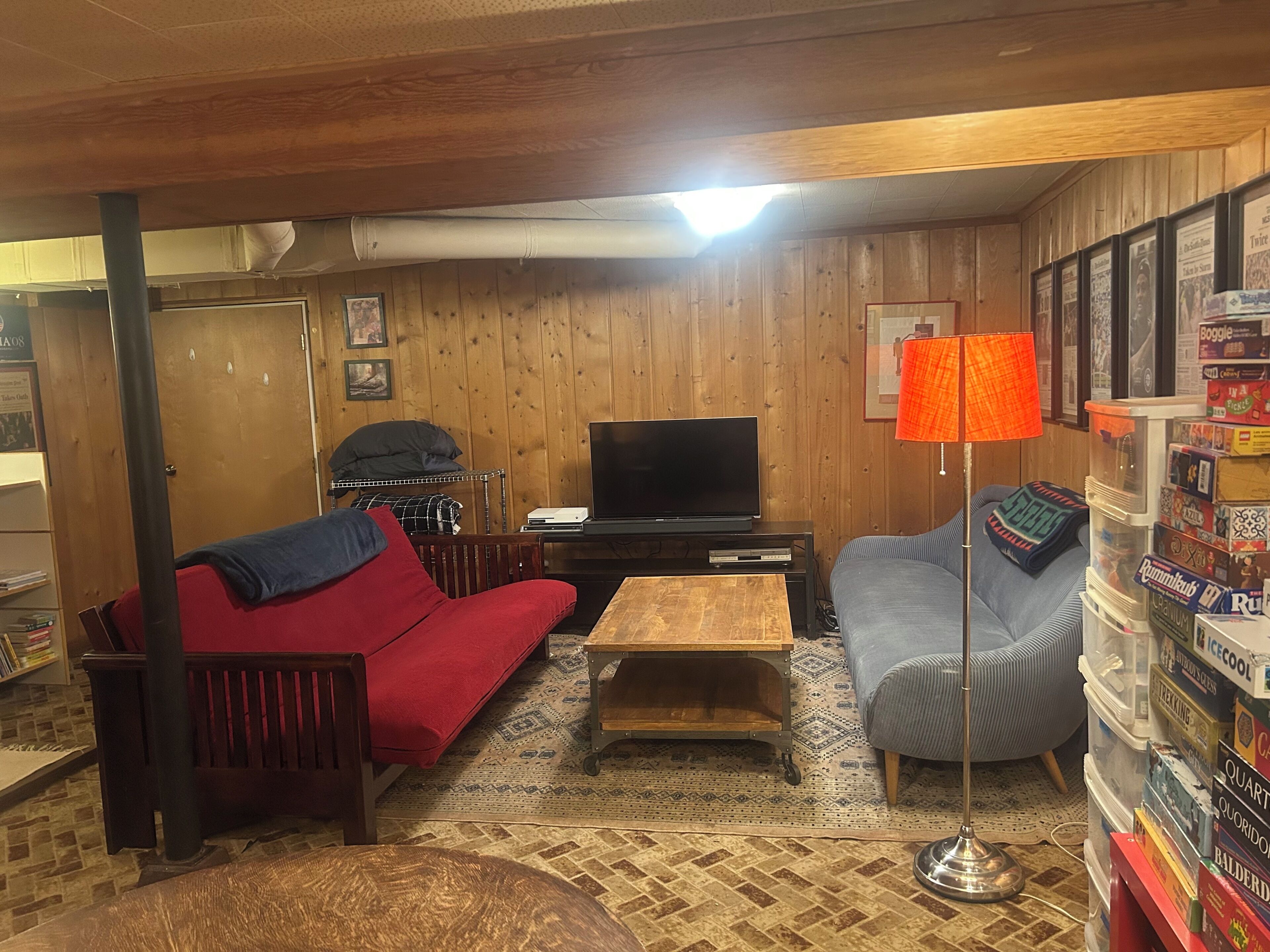 A cozy living room with a sofa, a television, a lamp, and a bookshelf.
