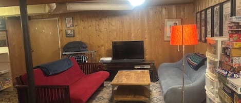 A cozy living room with a sofa, a television, a lamp, and a bookshelf.