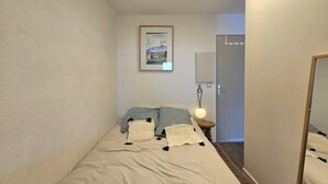 Une chambre à coucher avec un lit, des oreillers, une lampe de chevet, un tableau encadré au mur et une porte.