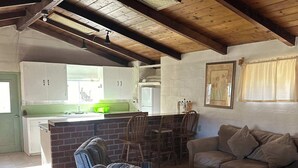 A rustic interior with a dining area, a sofa, and a kitchen in the background.
