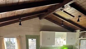A dining area with a long table and chairs, a kitchen with white cabinets and a green countertop, and a door with a window.