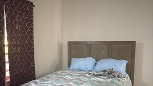 A bed with a wooden headboard, a patterned bedspread, and two pillows.