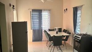 A compact kitchen with a dining area, a refrigerator, a microwave, and a gas stove.