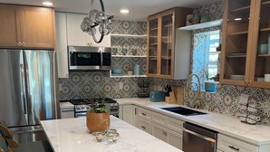 Una cucina moderna con isola centrale, elettrodomestici in acciaio inossidabile e una parete di fondo decorata.