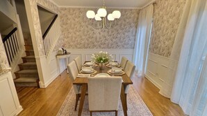 A dining room with a wooden table set for six, a chandelier, and a staircase leading to another level. - Elegant Historic Duplex in Old Town • Lincoln Park (Chicago)