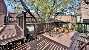 A wooden deck with potted plants, a wooden chair, and a view of a brick building. - Elegant Historic Duplex in Old Town • Lincoln Park (Chicago)