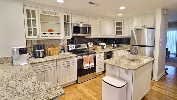 A modern kitchen with white cabinets, granite countertops, stainless steel appliances, and a central island. - Elegant Historic Duplex in Old Town • Lincoln Park (Chicago)