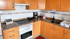 Eine Küche mit Holzausstattung, Backofen, Kaffeemaschine und Spüle.