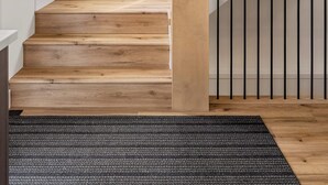A staircase with wooden steps and black railings, a potted plant, and a window with a view of trees. - The Shoreline | Luxury Escape w/ Rooftop & Hot Tub (Sylvan Lake)